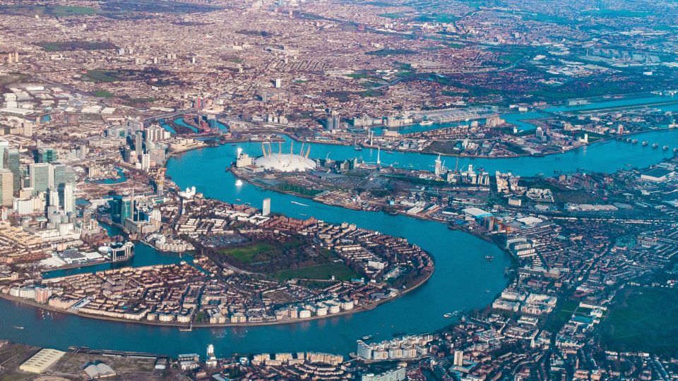 Aerial view of the blue river Thames snaking through London Docklands with the O2 Arena in the centre