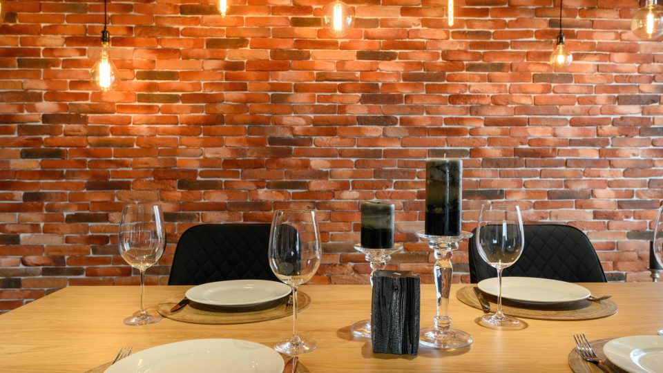 Modern luxurious dark gray and black kitchen with dining table by the red bick wall, truck shot