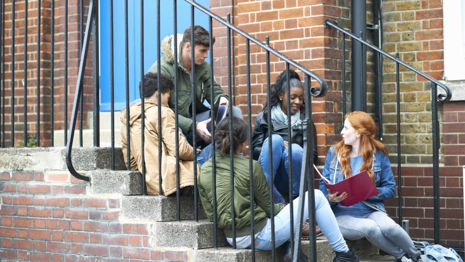 Young adult college students chatting and revising on campus stairs